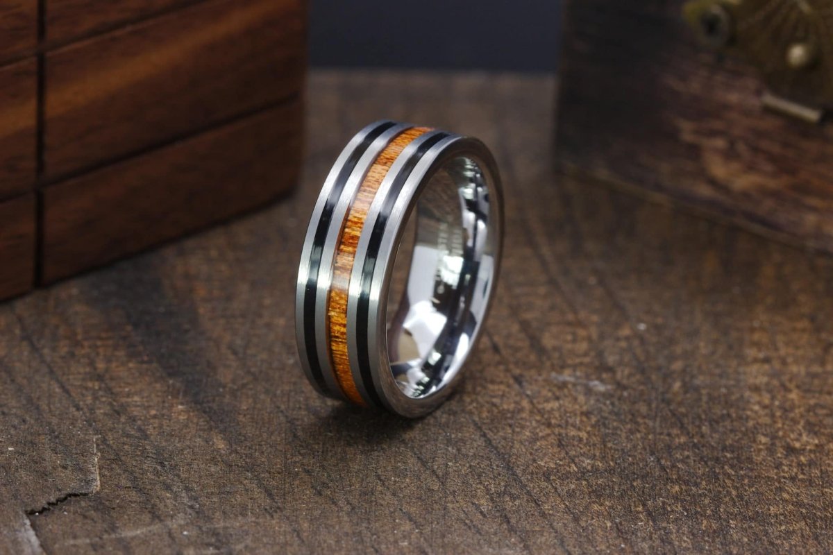 The Excavator, a sleek silver tungsten carbide scratch resistant ring with sleek black stripes and a center whiskey barrel wood inlay.