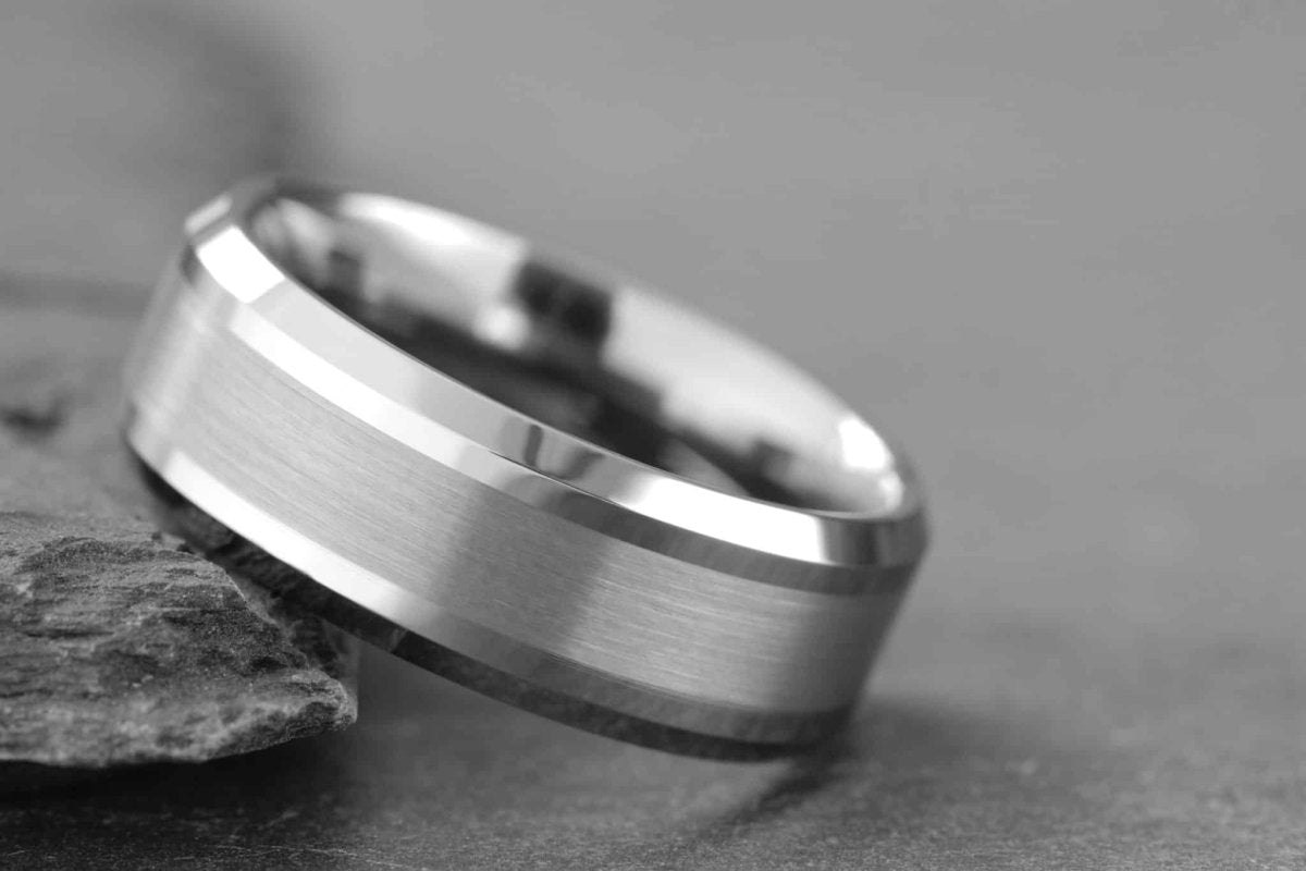 Silver wedding band laying on slate background