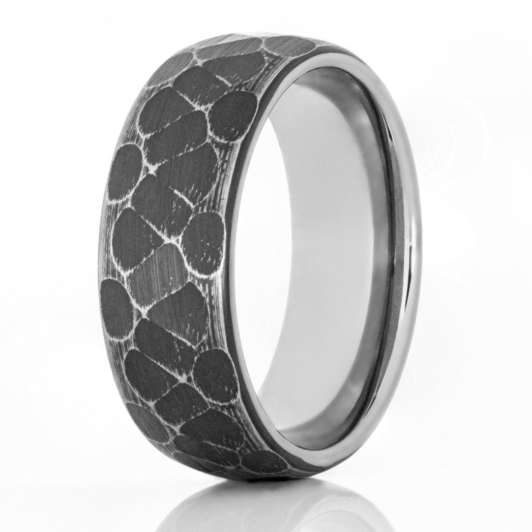 The Mentor, a silver and black titanium ring that features a brushed and hammered finish.